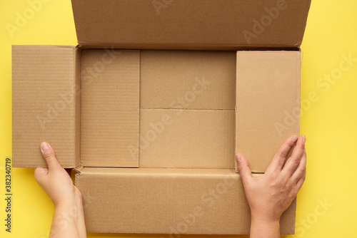female hands are holding an empty open box of brown cardboard, top view © nndanko