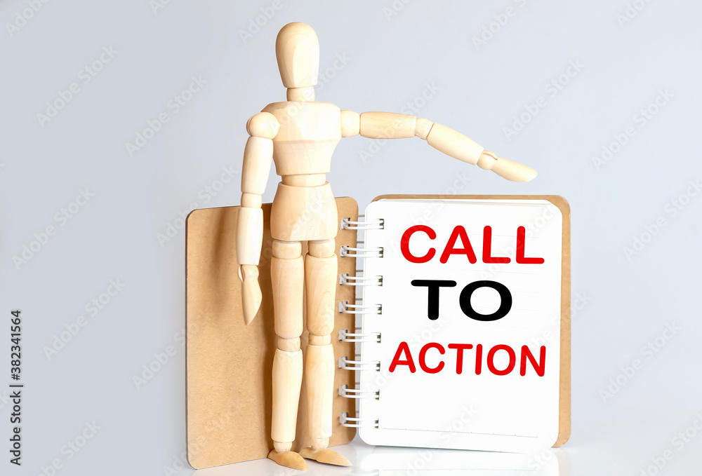 Wooden man shows with a hand to white notepad with text CALL TO ACTION Wooden man shows with a hand to white notepad with text CALL TO ACTION