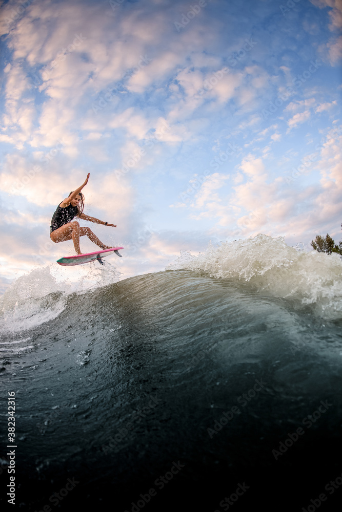 beautiful view of woman jumping over big splashing wave on surf style wakeboard. beautiful view of woman jumping over big splashing wave on surf style wakeboard.