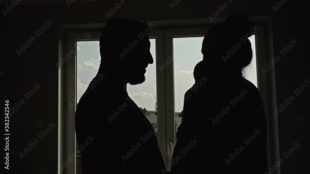 Silhouettes of loving parents with a baby on the background of a window at night. Silhouettes of loving parents with a baby on the background of a window at night.