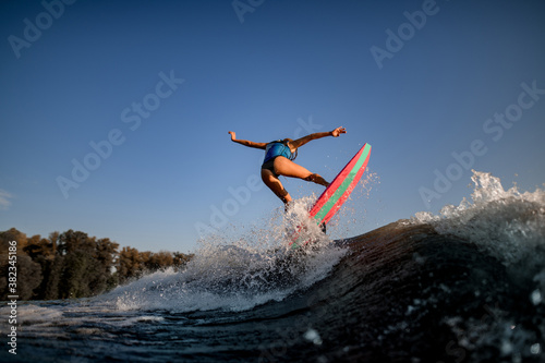 attractive sexy woman jumping on big splashing wave on surf style wakeboard.