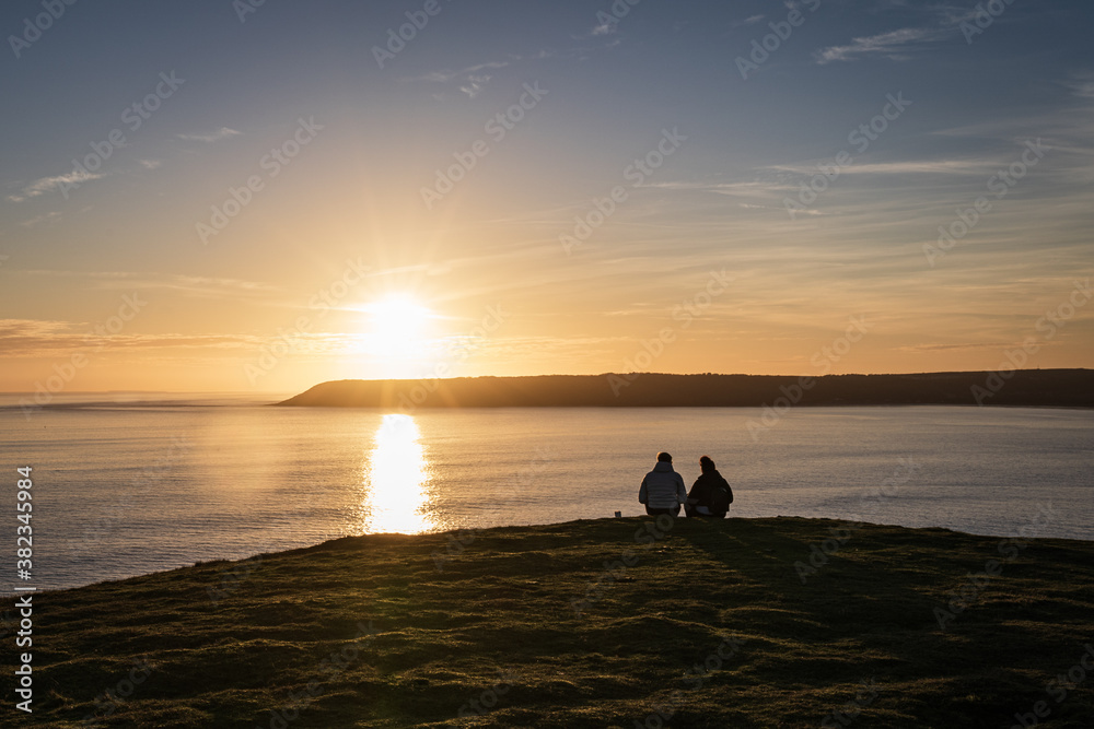 People watching sunset at Rhossili Bay, Worm's head, Gower Peninsula beach, Swansea, Wales, United Kingdom, Europe