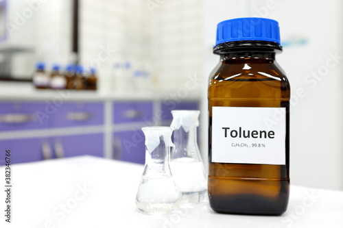 Selective focus of toluene liquid chemical compound in dark glass bottle inside a chemistry laboratory with copy space. Aromatic hydrocarbon used in petrochemical industry. photo