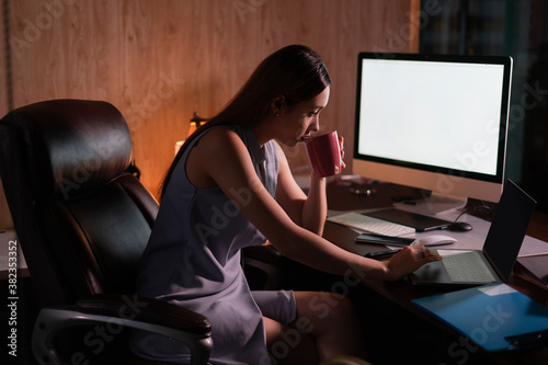 Beautiful mixed race woman working overtime at night in office with computer.