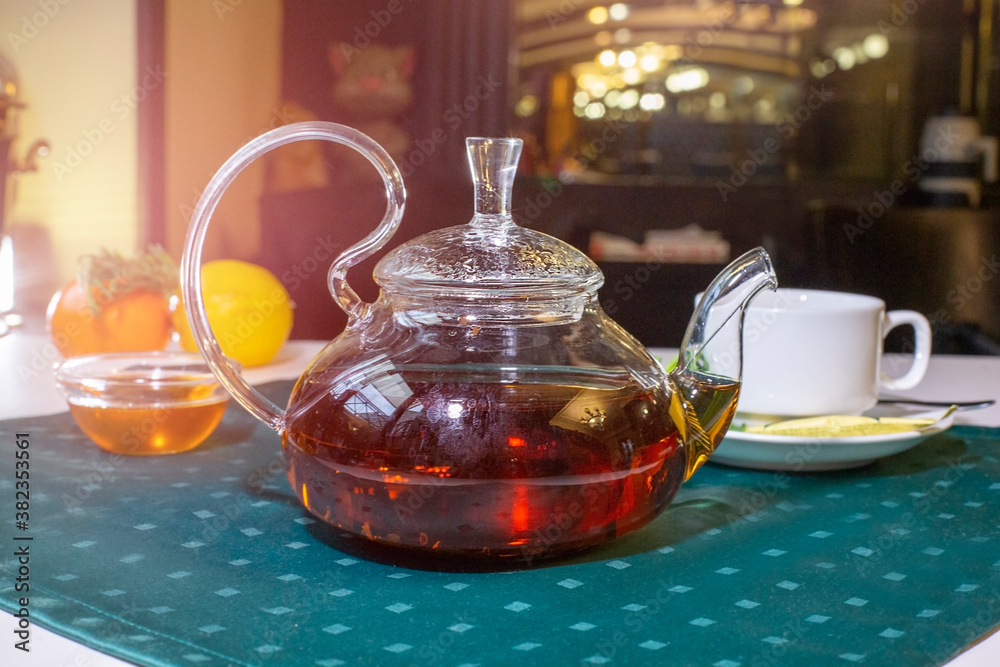 Aromatic hot green tea in a glass teapot with a warm blurry background with honey and fresh mint leaves. Served table with tea in a cafe Aromatic hot green tea in a glass teapot with a warm blurry background with honey and fresh mint leaves. Served table with tea in a cafe