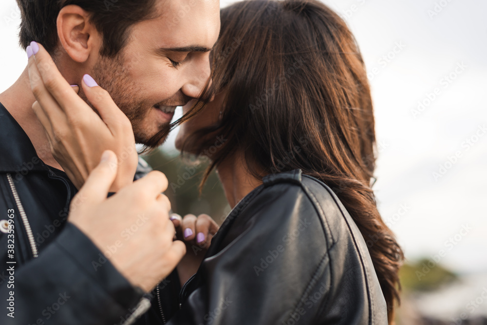 Fototapeta premium Selective focus of woman in leather jacket touching boyfriend outdoors