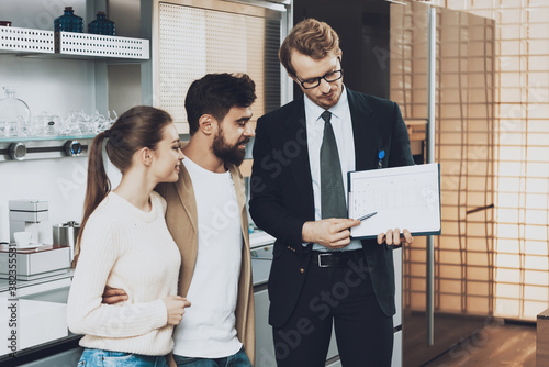 A salesman in a suit shows buyers the layout.