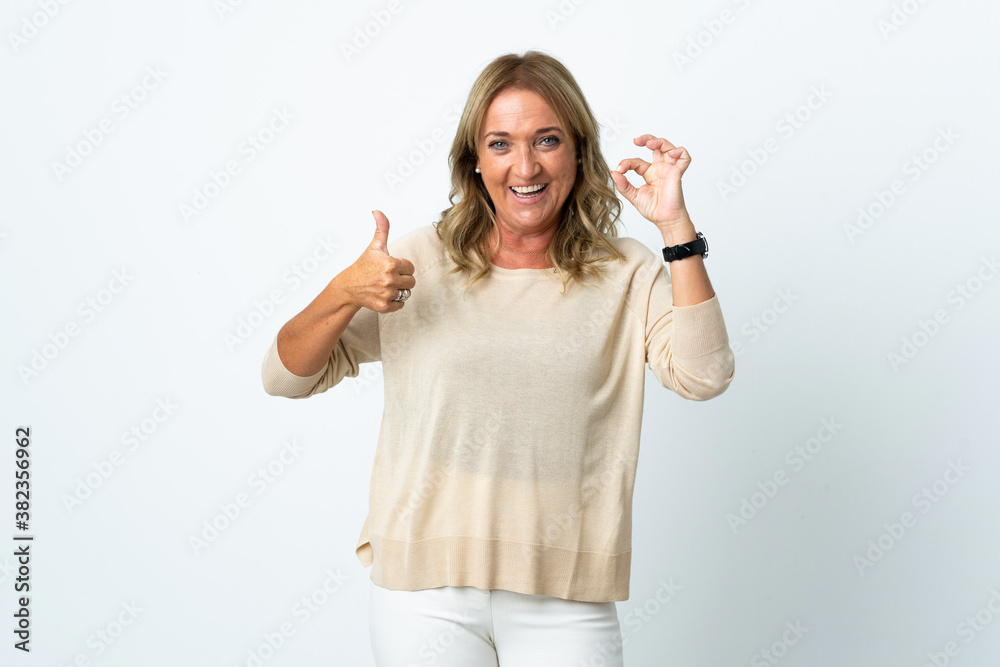 Obraz premium Middle aged blonde woman over isolated white background showing ok sign and thumb up gesture