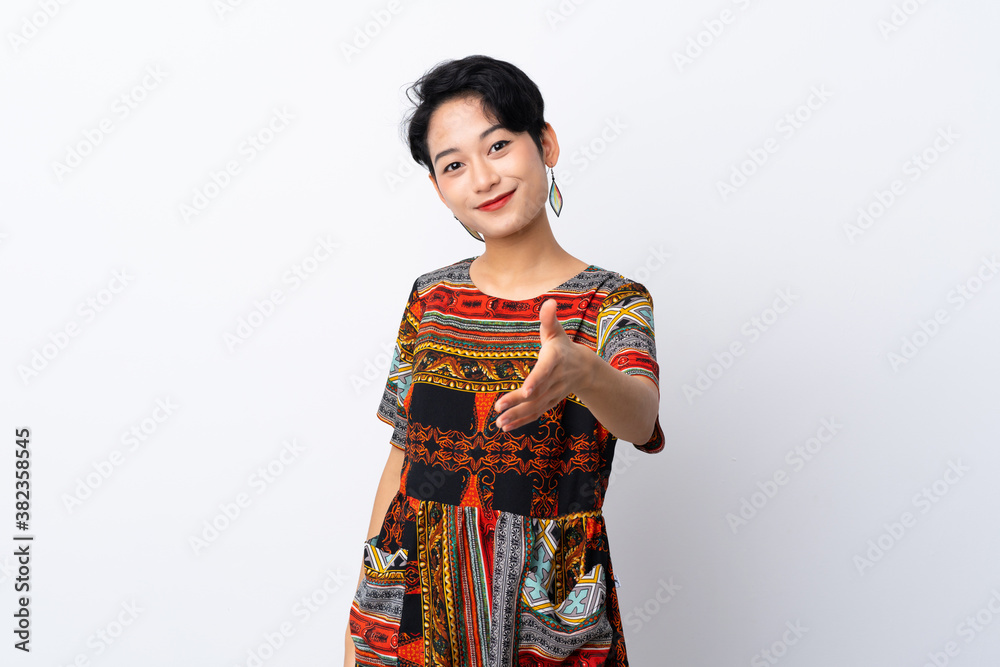 Young Asian girl with a colorful dress over isolated white background shaking hands for closing a good deal