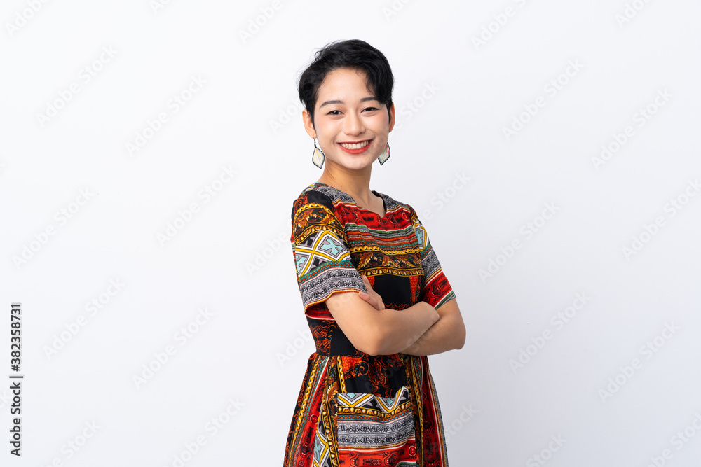 Young Asian girl with a colorful dress over isolated white background with arms crossed and looking forward Young Asian girl with a colorful dress over isolated white background with arms crossed and looking forward