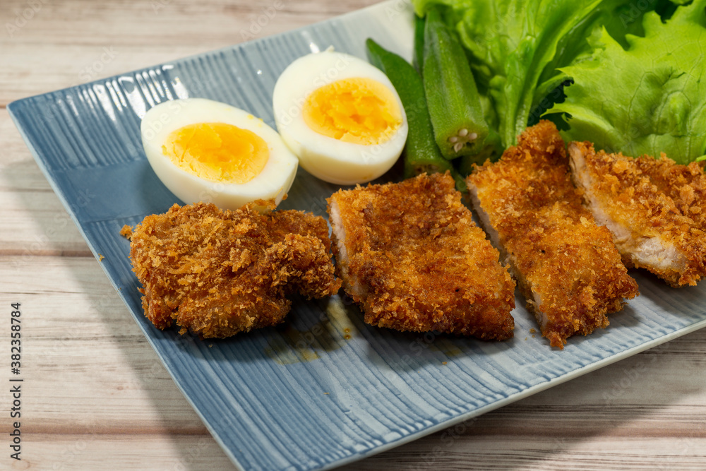 Homemade Japanese pork cutlet served with boiled egg, okra and baby leaves Homemade Japanese pork cutlet served with boiled egg, okra and baby leaves