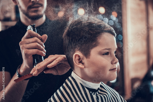 Boy in barbershop while he is sprayed with water photo