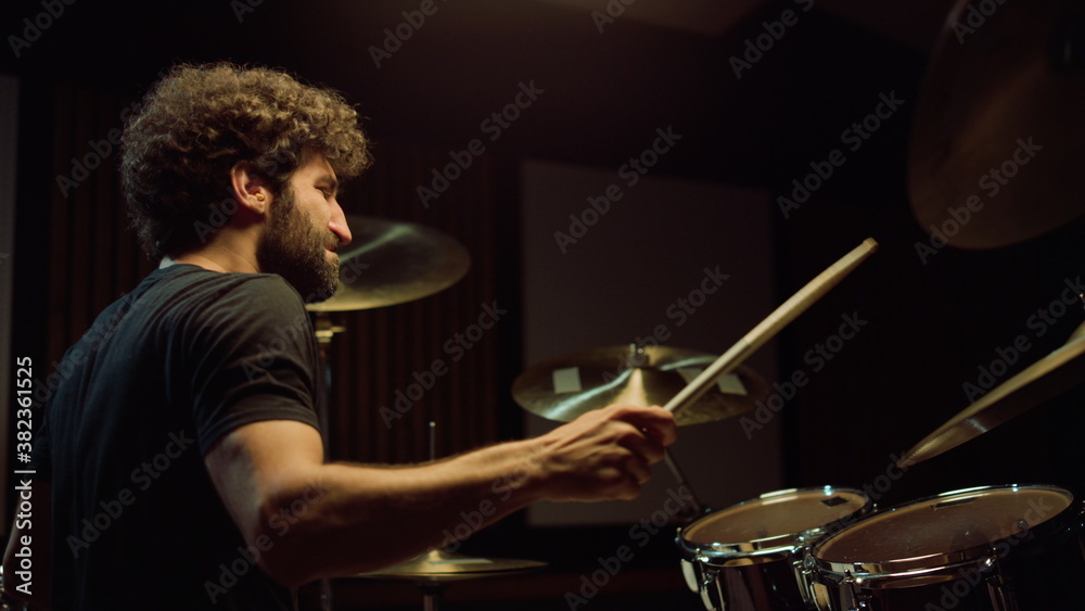 Naklejka premium Cheerful artist hitting drum cymbals in studio. Closeup drummer playing on stage