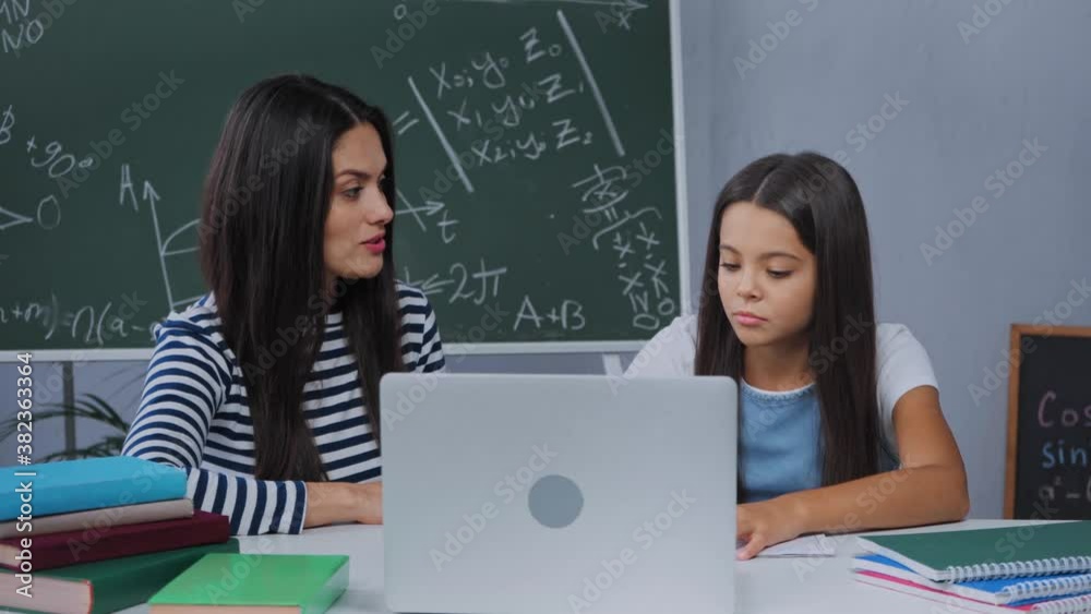mother talking with kid near laptop while explaining homework mother talking with kid near laptop while explaining homework