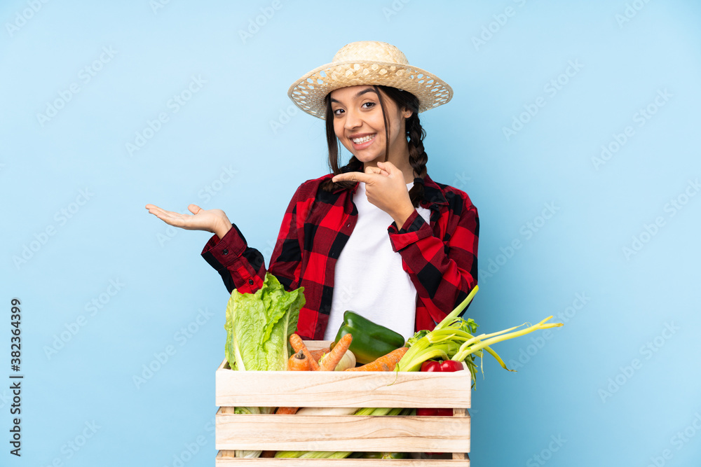 Young farmer Woman holding fresh vegetables in a wooden basket holding copyspace imaginary on the palm to insert an ad
