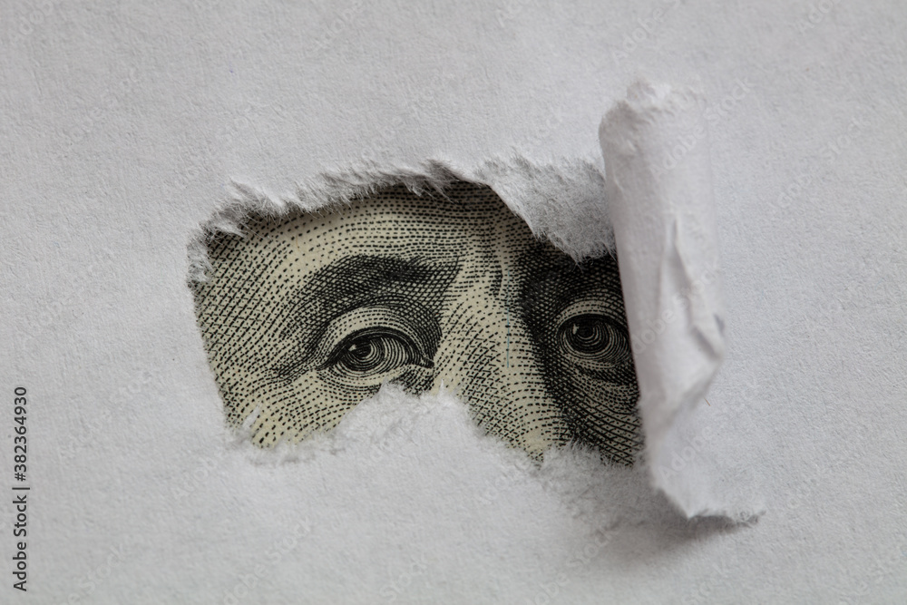 Benjamin Franklin macro peeking through torn white paper