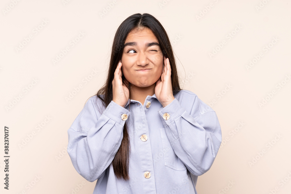 Young Indian woman isolated on beige background frustrated and covering ears Young Indian woman isolated on beige background frustrated and covering ears