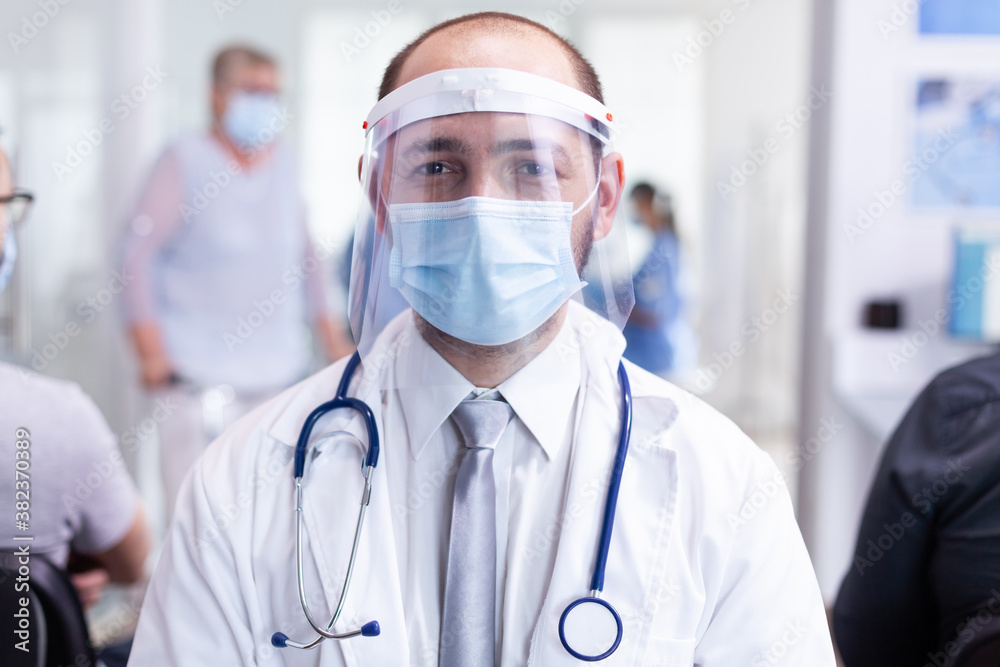 Portrait of tired medic in hallway of private hospital during coronavirus quaraintine. Doctor in hospital waiting room with medical mask protection epidemic against covid-19. Medical examination room. Portrait of tired medic in hallway of private hospital during coronavirus quaraintine. Doctor in hospital waiting room with medical mask protection epidemic against covid-19. Medical examination room.