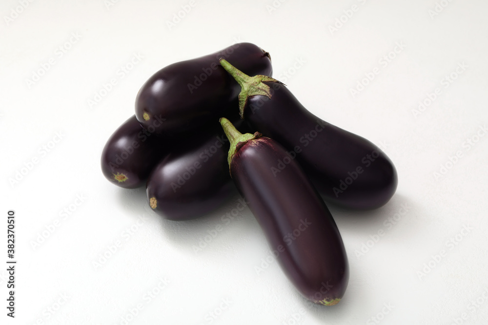 Pile of raw ripe eggplants on white table Pile of raw ripe eggplants on white table
