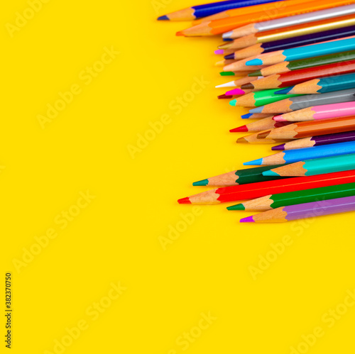 Many colorful pencils on yellow background