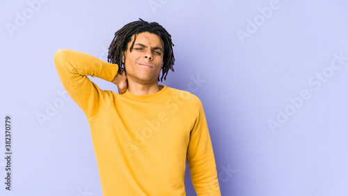 Young black man wearing rasta hairstyle having a neck pain due to stress, massaging and touching it with hand. © Asier