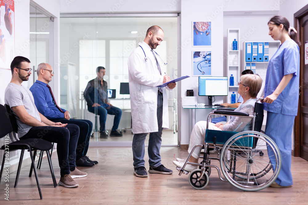 Doctor checking diagnosis of disabled senior woman in wheelchair. Medical staff in hospital hallway with invalid patient. Man in medical examination room. Doctor checking diagnosis of disabled senior woman in wheelchair. Medical staff in hospital hallway with invalid patient. Man in medical examination room.