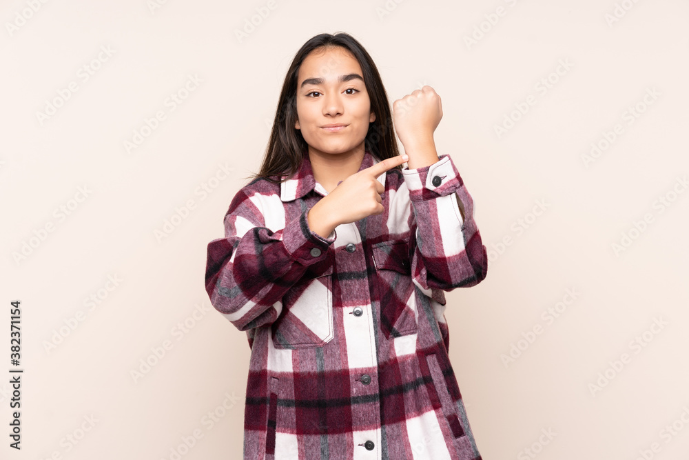 Young Indian woman isolated on beige background making the gesture of being late Young Indian woman isolated on beige background making the gesture of being late