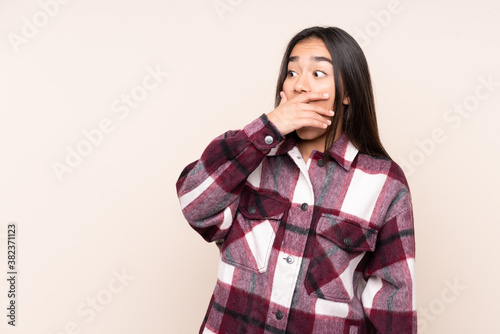 Young Indian woman isolated on beige background doing surprise gesture while looking to the side