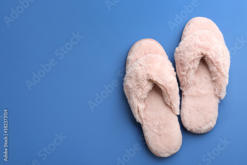 Pair of stylish soft slippers on blue background, flat lay. Space for text