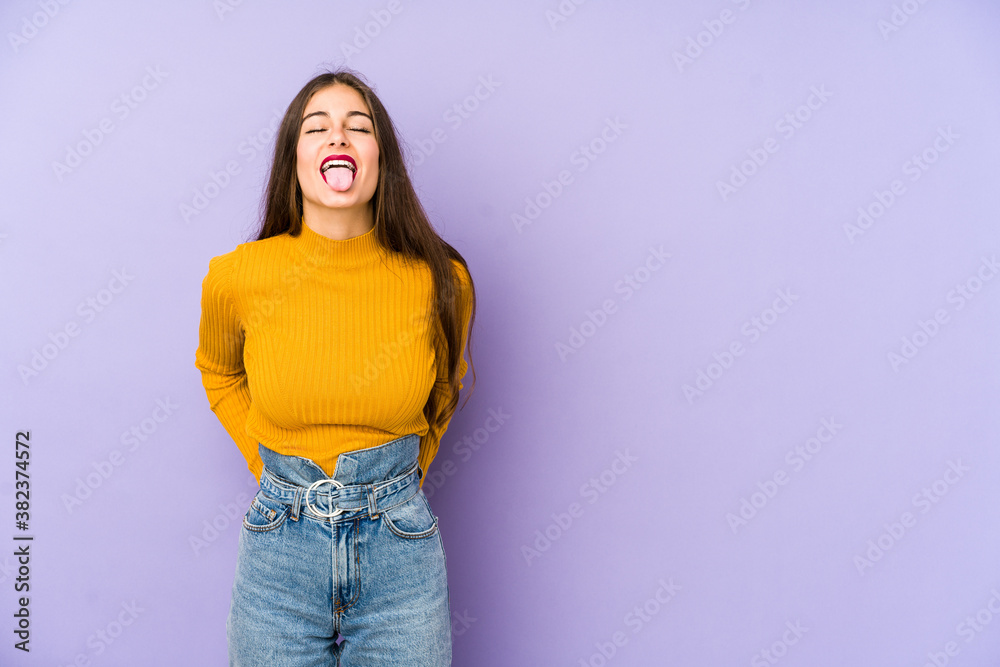 Young caucasian woman isolated on purple background funny and friendly sticking out tongue. Young caucasian woman isolated on purple background funny and friendly sticking out tongue.