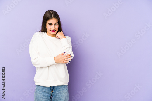 Young caucasian woman isolated on purple background massaging elbow, suffering after a bad movement.