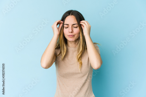 Young caucasian woman isolated on blue background touching temples and having headache.