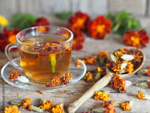Dried flowers of red flowers of calendula with a cup of medicinal tea on a wooden background.Herbal picking season.