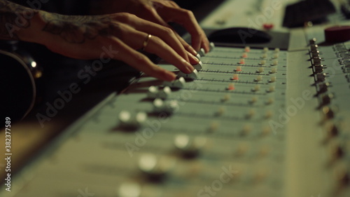 Sound engineer moving sliders on control desk. Man hands touching soundboard.