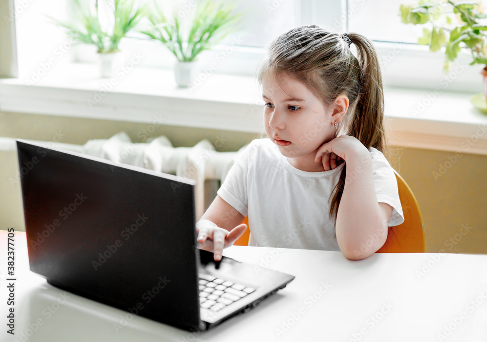 
little girl sitting at a laptop
