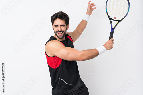 Young handsome man with beard over isolated white background playing tennis © luismolinero