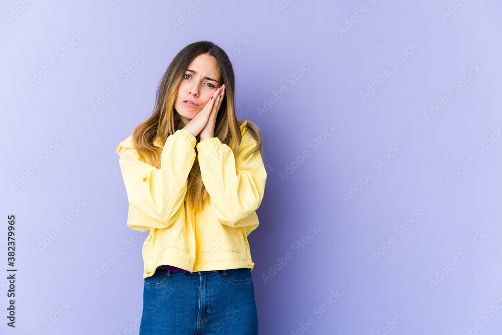 Young caucasian woman isolated on purple background yawning showing a tired gesture covering mouth with hand. Young caucasian woman isolated on purple background yawning showing a tired gesture covering mouth with hand.