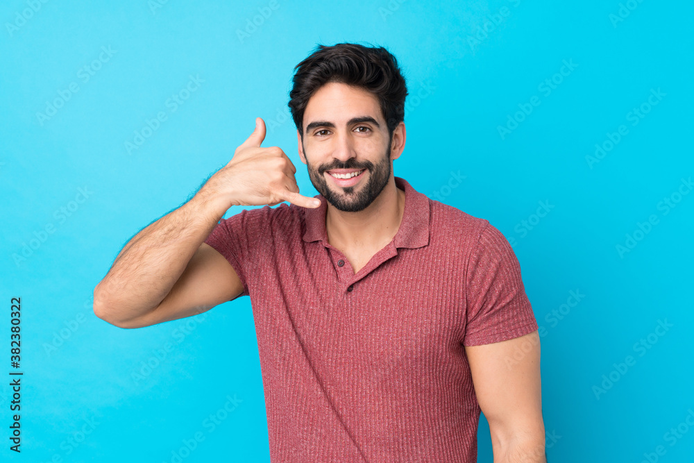 Young handsome man with beard over isolated blue background making phone gesture. Call me back sign Young handsome man with beard over isolated blue background making phone gesture. Call me back sign