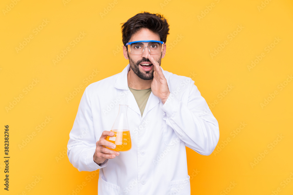 Young scientific man over isolated yellow background shouting with mouth wide open Young scientific man over isolated yellow background shouting with mouth wide open