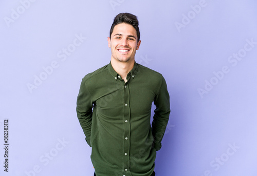 Young caucasian man isolated on purple background happy, smiling and cheerful.