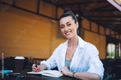 Positive woman taking notes in notebook