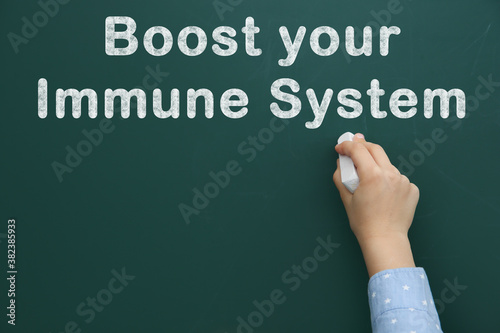 Boost Your Immune System. Child writing text on green chalkboard, closeup