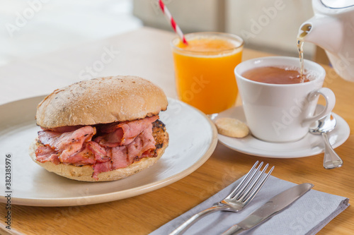 Bacon rashers in a toasted bun with tea and orange juice