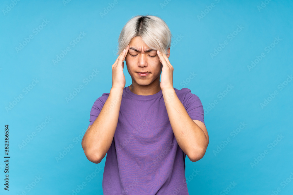 Young asian man over isolated blue background with headache Young asian man over isolated blue background with headache