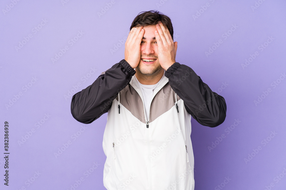 Young man isolated on purple background having fun covering half of face with palm. Young man isolated on purple background having fun covering half of face with palm.