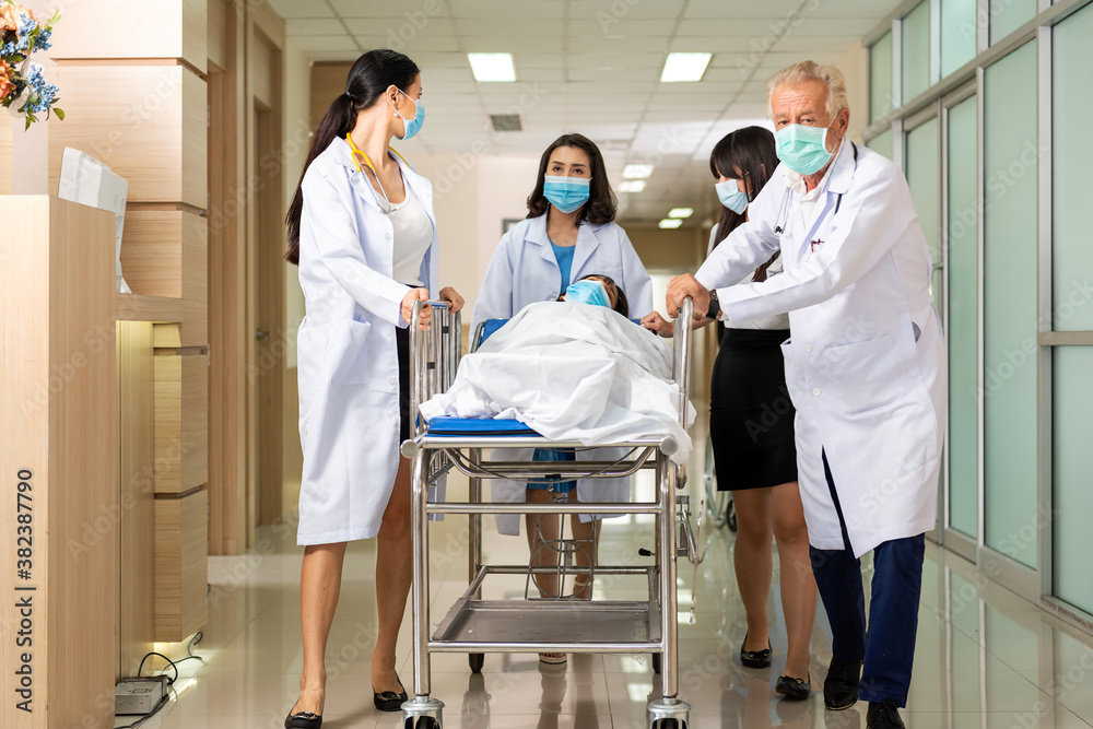 Fototapeta premium Team medical doctor pushing stretcher gurney bed corridor with female patient in hospital. Health care Concept.