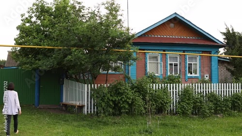 A young woman is going in a gates on the street in the russian village.