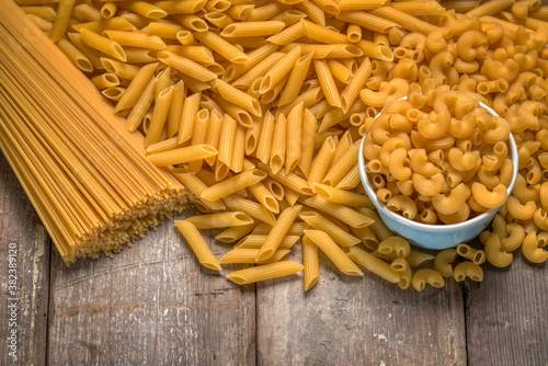Different types of dried pasta on rustic wooden table