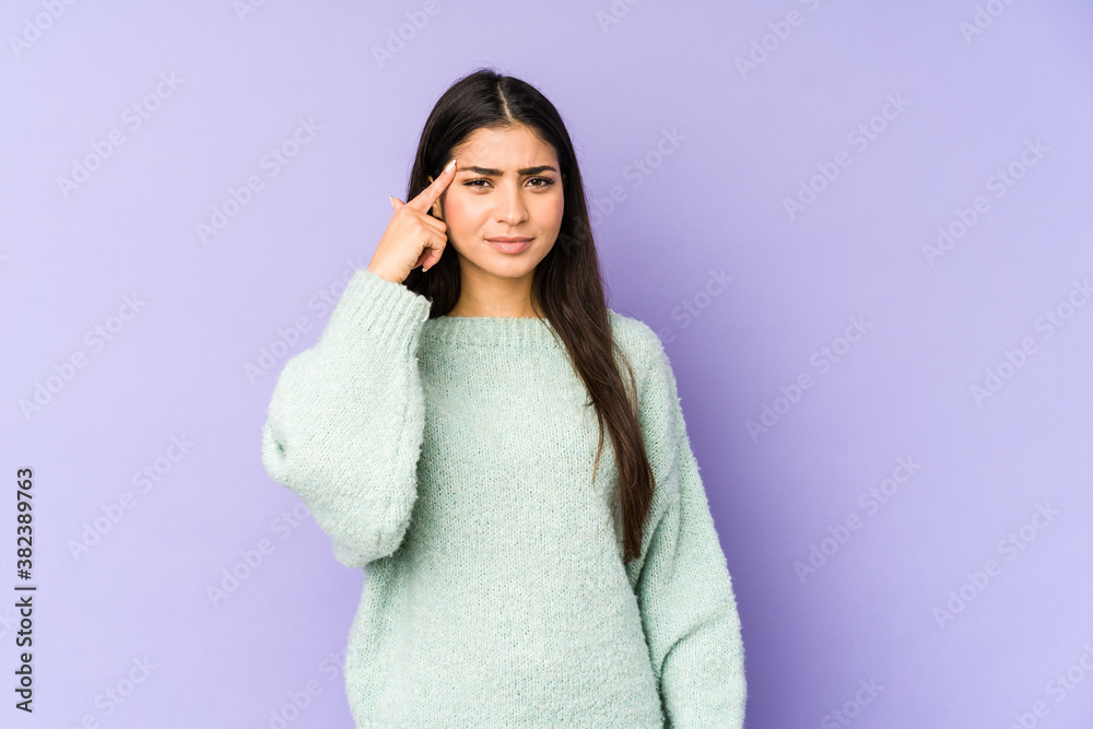 Young indian woman isolated on purple background pointing temple with finger, thinking, focused on a task. Young indian woman isolated on purple background pointing temple with finger, thinking, focused on a task.