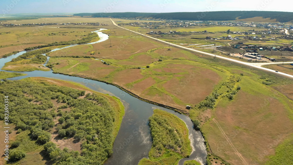 Waving river of blue colour surrounded by forests and fields Waving river of blue colour surrounded by forests and fields